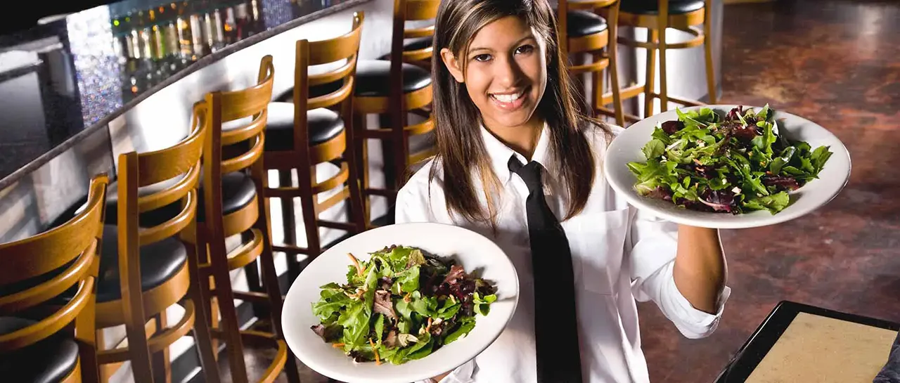 Female server holding two salad plates